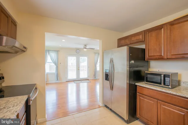 a kitchen with stainless steel appliances granite countertop a refrigerator a stove and a sink with wooden floor