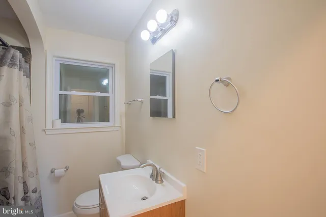 a bathroom with a toilet sink a mirror and vanity
