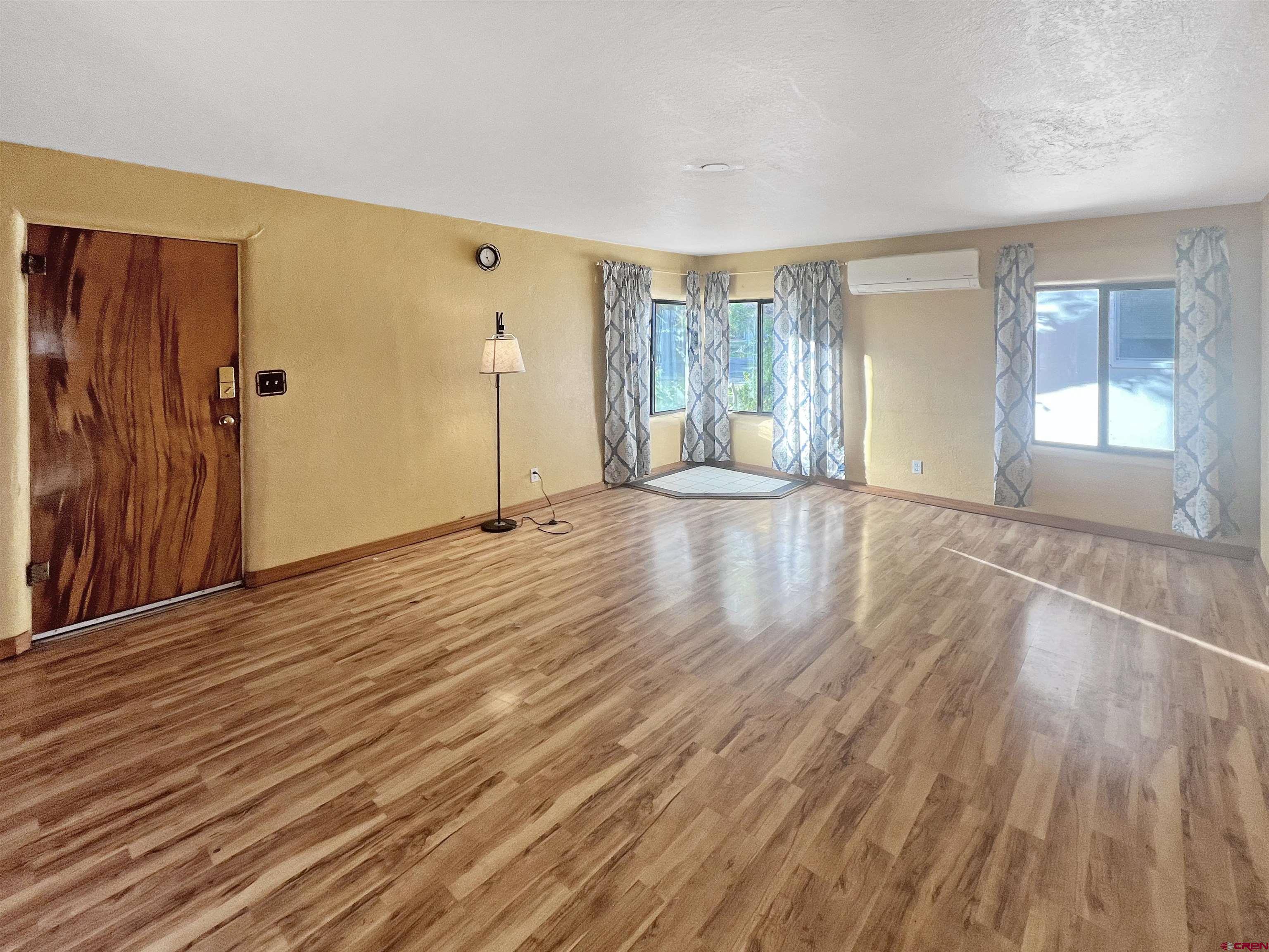 112 North Adams Street Cortez, CO 81321 - Photo 3 of 20 a view of an empty room with wooden floor and a window