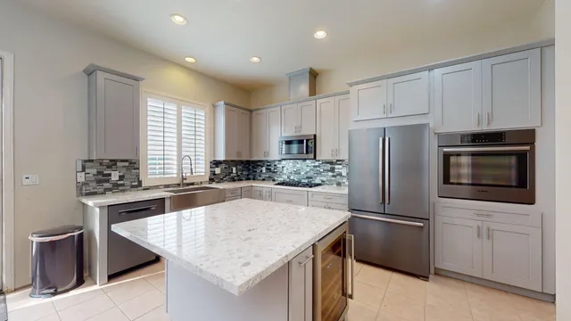 a kitchen with kitchen island granite countertop a center island stainless steel appliances cabinets and a window