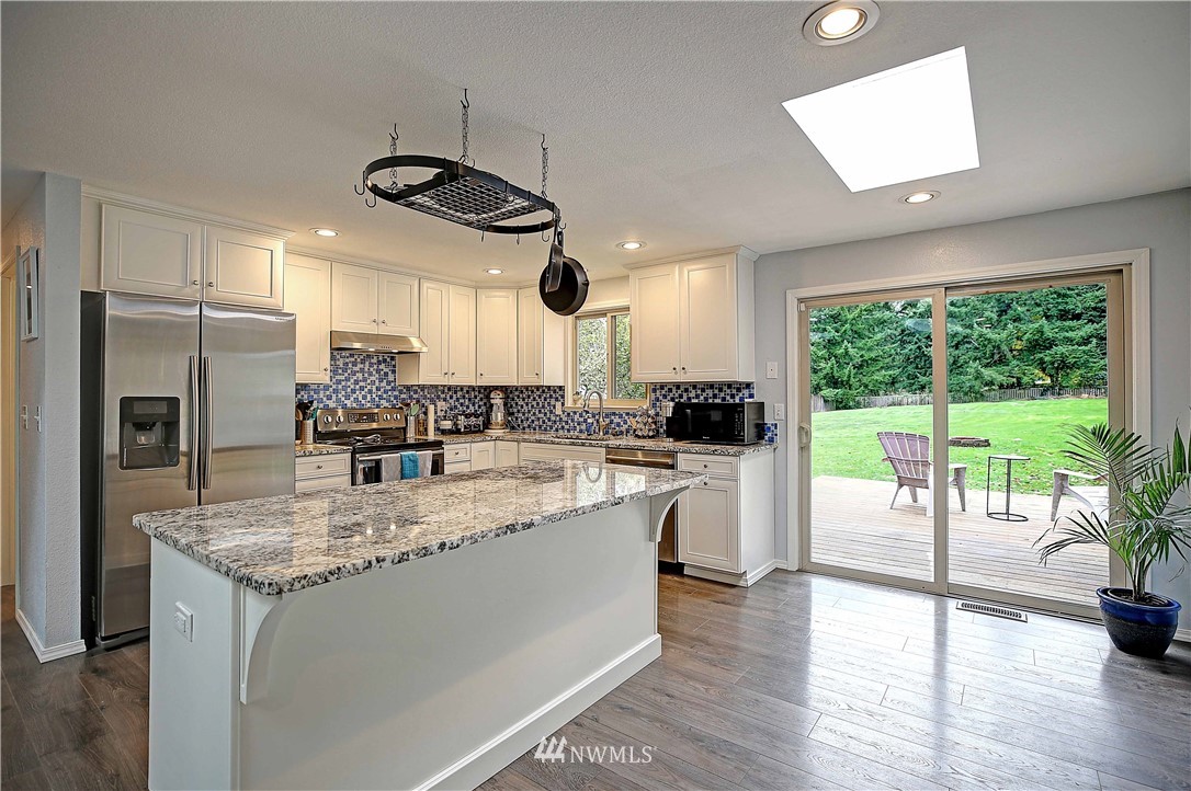 4415 212th Street Southeast Bothell, WA 98021 - Photo 5 of 29 a kitchen with a counter top space a sink a refrigerator a counter space and wooden floor