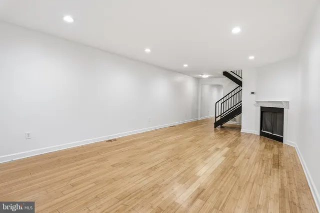 a view of empty room with wooden floor and fireplace