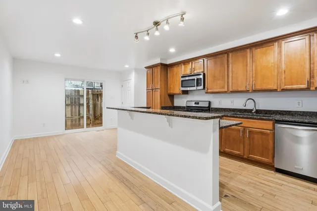 a kitchen with granite countertop wooden floors stainless steel appliances a sink