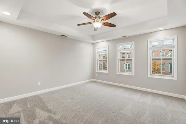 an empty room with ceiling fan and windows