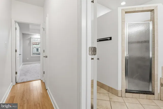 a view of a hallway with wooden floor and a bathroom