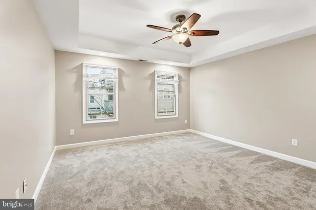 an empty room with windows and fan