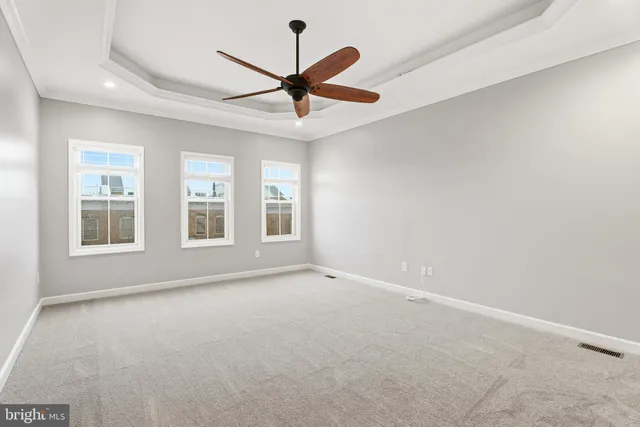 an empty room with ceiling fan and windows