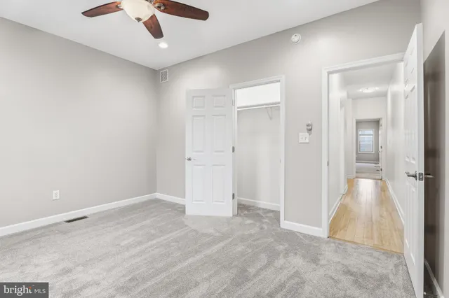 an empty room with closet and a ceiling fan
