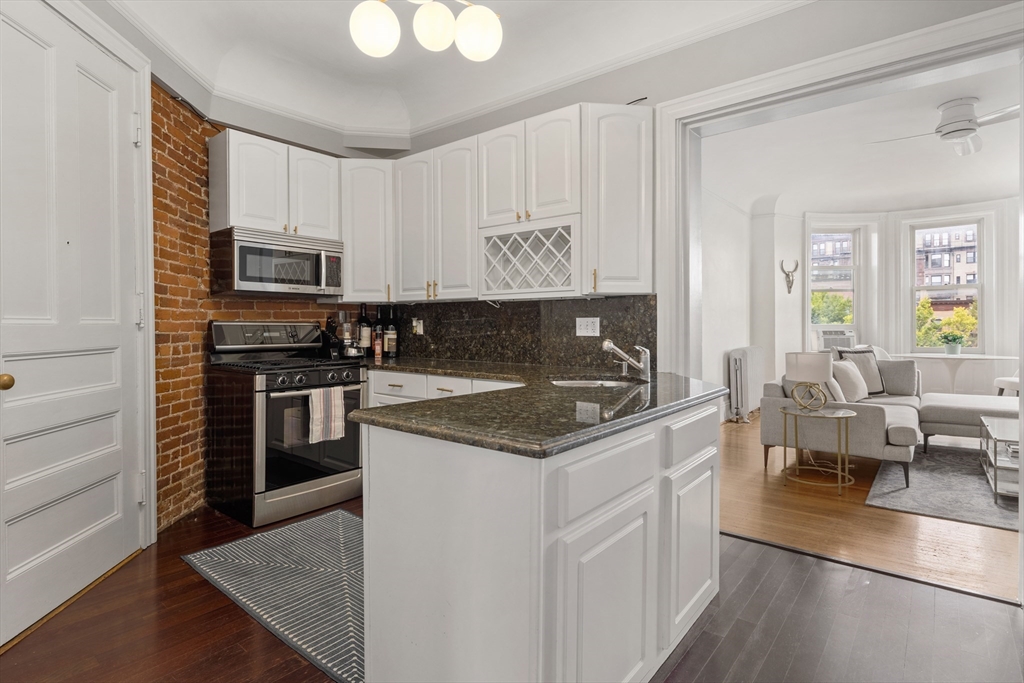 362 Commonwealth Avenue, Unit 4A Boston, MA 02115 - Photo 13 of 23 a kitchen with stainless steel appliances granite countertop a stove top oven a sink dishwasher a dining table and chairs with wooden floor