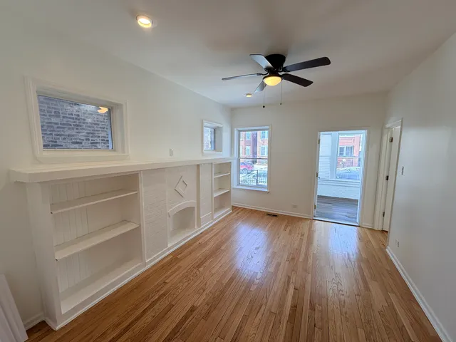 a view of an empty room with window and wooden floor