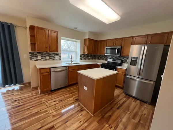 a kitchen with stainless steel appliances a refrigerator a sink a stove top oven a refrigerator and cabinets