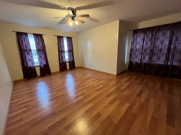 a view of an empty room with window and wooden floor