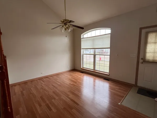 an empty room with wooden floor fan and windows