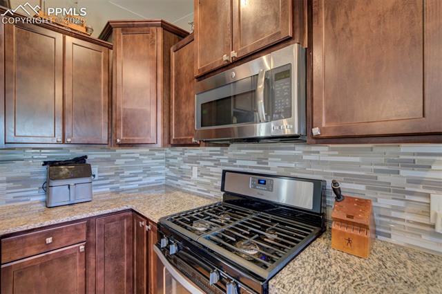 5860 Curtis Road Peyton, CO 80831 - Photo 14 of 28 Kitchen with tasteful backsplash, stainless steel appliances, and light stone counters