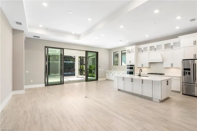 a large white kitchen with granite countertop a stove top oven a sink and a granite counter top