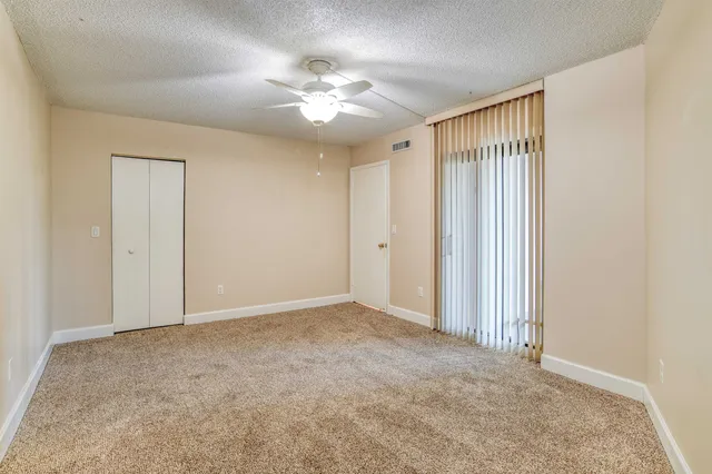 an empty room with a chandelier fan and windows