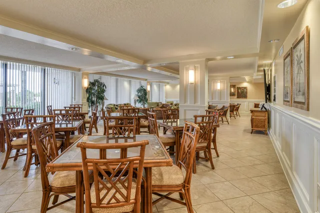 a room with lots of chairs a desk and large windows