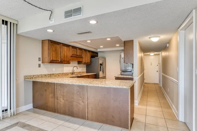 a large kitchen with stainless steel appliances kitchen island granite countertop a refrigerator and a sink