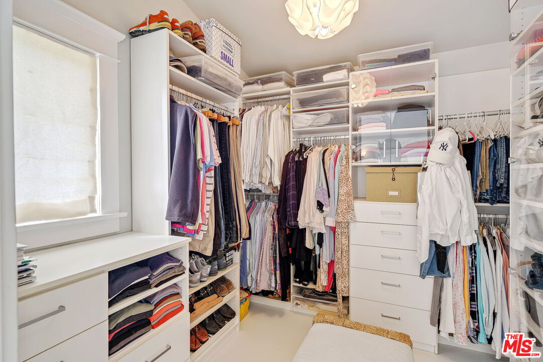 a view of walk in closet with clothes and shoes
