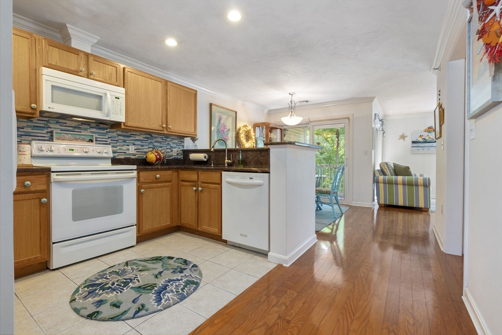 35 Collins Street, Unit 75 Danvers, MA 01923 - Photo 16 of 31 a kitchen with stainless steel appliances granite countertop a stove top oven a refrigerator a sink and white cabinets with wooden floor