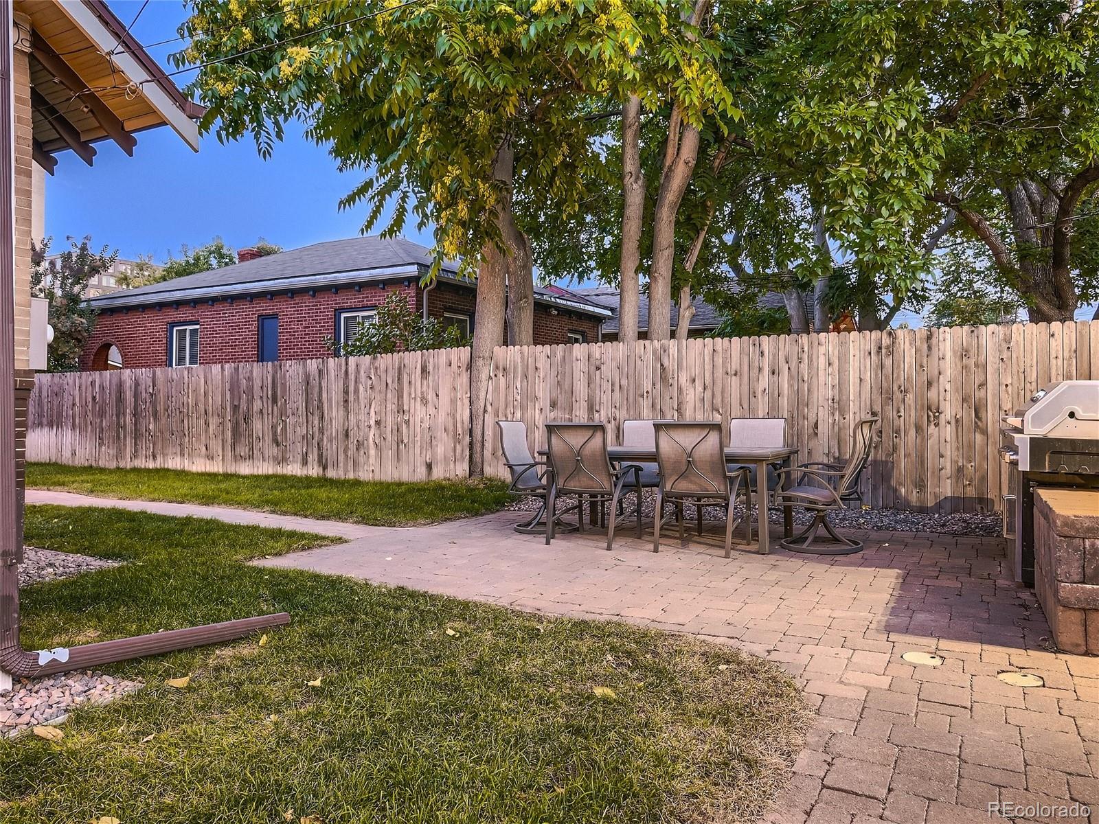 1031 Harrison Street Denver, CO 80206 - Photo 29 of 32 a view of a backyard with table and chairs potted plants and a large tree