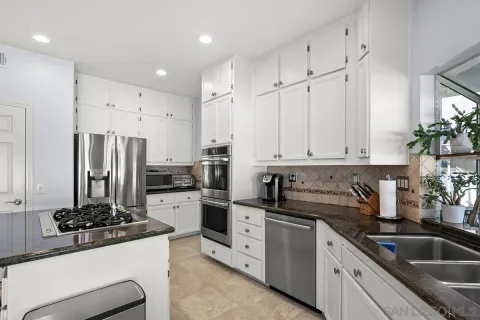 a kitchen with white cabinets and stainless steel appliances