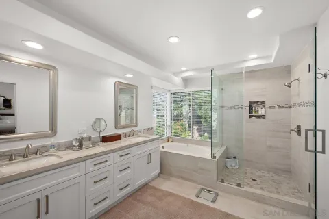 a spacious bathroom with a double vanity sink toilet mirror and bathtub
