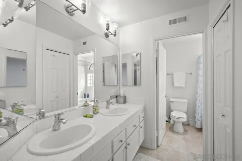 a bathroom with a double vanity sink toilet and a mirror