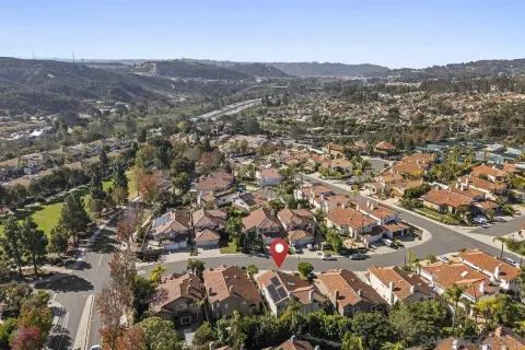 an aerial view of residential house with parking and trees