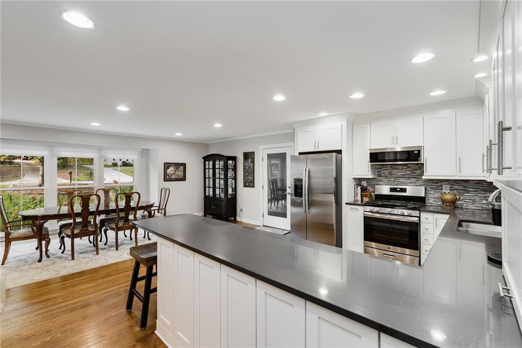 6555 Wright Road Northeast Sandy Springs, GA 30328 - Photo 9 of 40 a kitchen with stainless steel appliances granite countertop a refrigerator a stove a sink a dining table and chairs with wooden floor