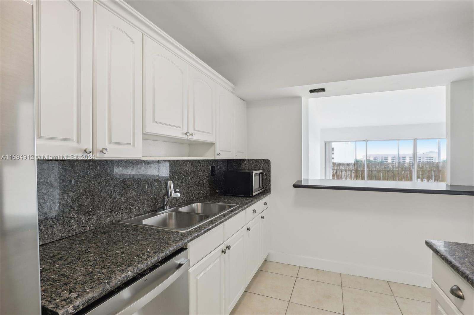 550 Ocean Drive, Unit 9F Key Biscayne, FL 33149 - Photo 26 of 37 a kitchen with granite countertop a sink a stove and cabinets