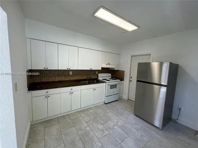 a kitchen with a refrigerator and white cabinets