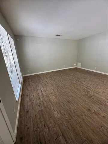 a view of an empty room with wooden floor and stairs