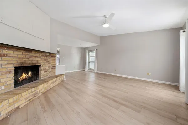 a view of an empty room with wooden floor fireplace and a window