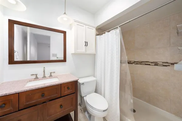 a bathroom with a toilet a sink tub and mirror