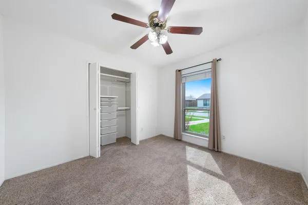 an empty room with ceiling fan and windows