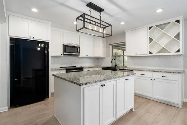 a kitchen with granite countertop a sink stainless steel appliances and cabinets