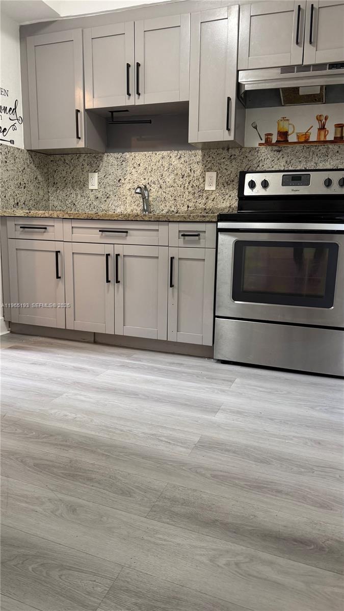 2238 Northwest 5th Street, Unit 1 Miami, FL 33125 - Photo 3 of 18 a kitchen with granite countertop cabinets stainless steel appliances and wooden floor
