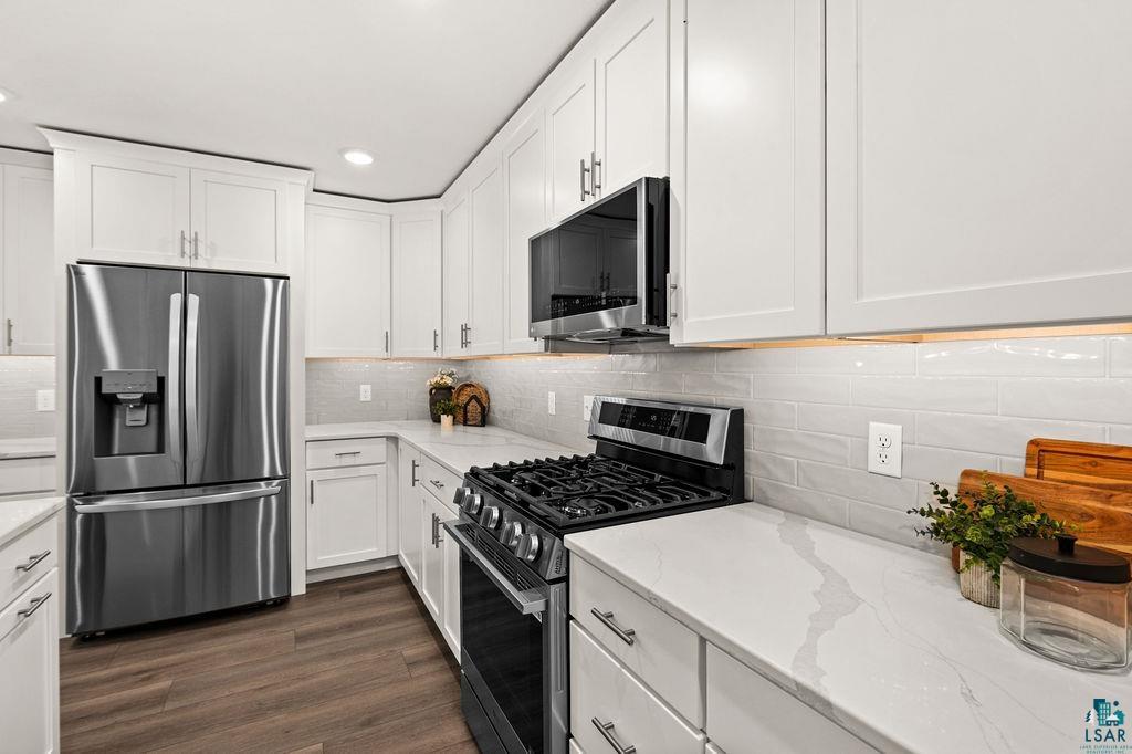 3971 Haines Road Hermantown, MN 55811 - Photo 8 of 34 Kitchen featuring white shaker-style cabinetry, stainless steel appliances, light-toned countertops, and wood-finish flooring