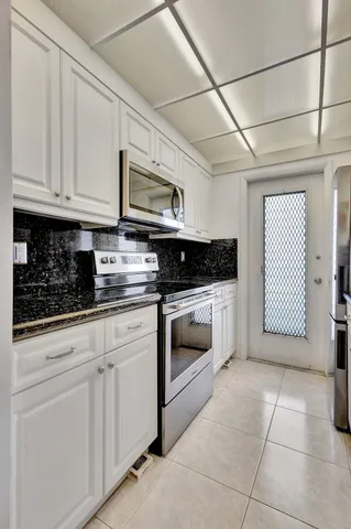 a kitchen with stainless steel appliances granite countertop a stove a sink and a white cabinets