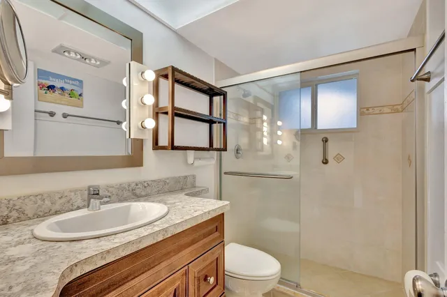 a bathroom with a granite countertop sink toilet a mirror and shower