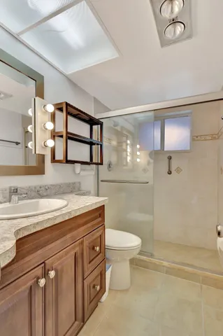 a bathroom with a granite countertop sink a toilet a mirror and shower