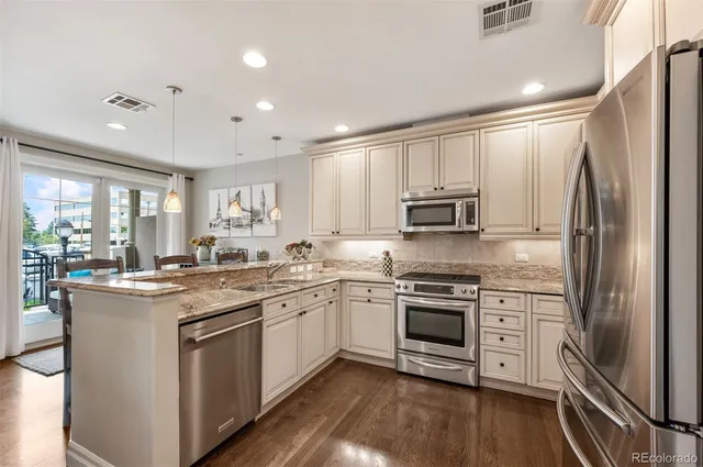 a kitchen with stainless steel appliances granite countertop a stove top oven a sink and dishwasher a refrigerator with wooden floor