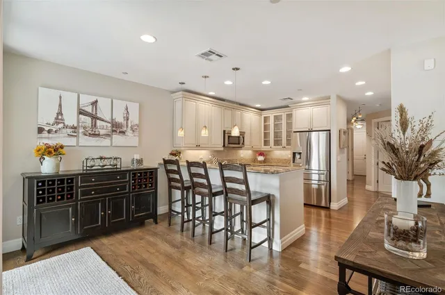 a kitchen with stainless steel appliances kitchen island granite countertop a stove a sink a refrigerator and chairs