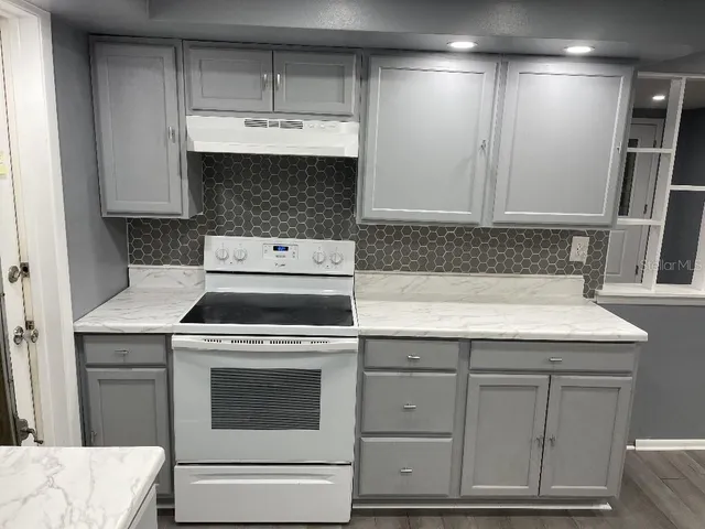 a kitchen with granite countertop a sink stove and cabinets