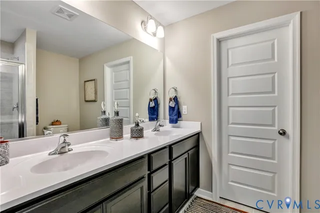 a bathroom with a double vanity sink a mirror and a shower