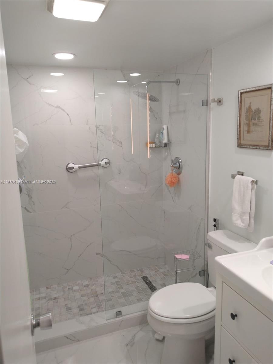 3510 Oaks Way, Unit 509 Pompano Beach, FL 33069 - Photo 28 of 36 a bathroom with a granite countertop sink a toilet and shower