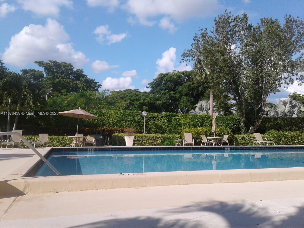 3510 Oaks Way, Unit 509 Pompano Beach, FL 33069 - Photo 8 of 36 a view of a swimming pool with a patio and a yard