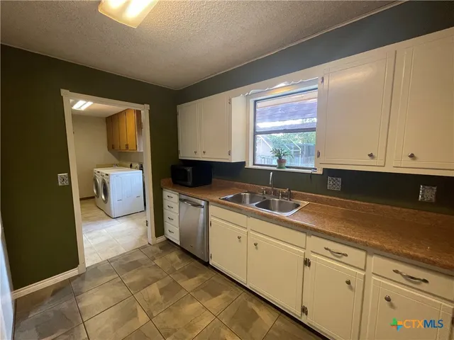 a kitchen with a sink a counter top space stainless steel appliances and cabinets