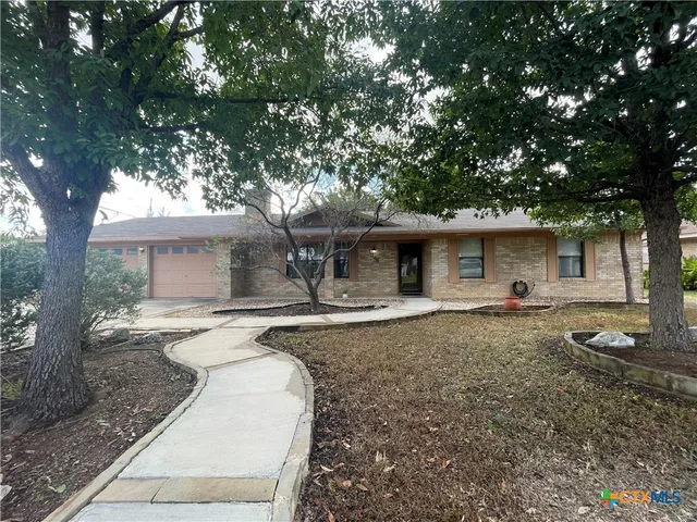 a front view of a house with a yard and trees